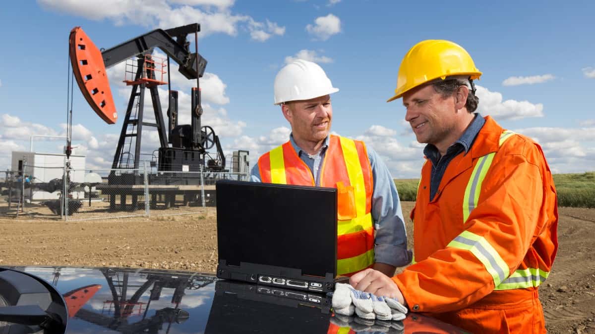 Two white male workmen working on site at an oil rig